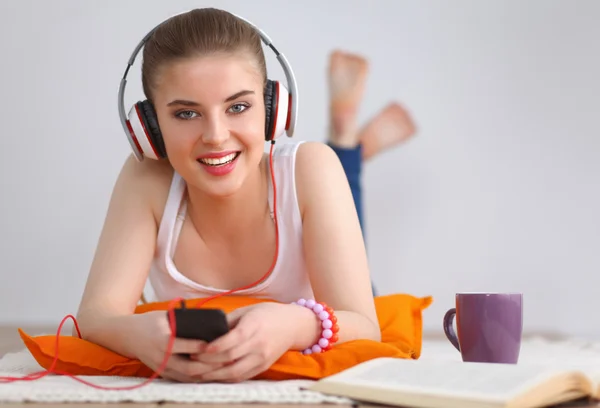 Young woman lying on floor and listen to music — Stock Photo, Image