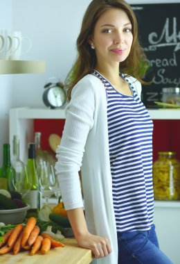 Mutfakta yemek yapmak için tablet bilgisayar kullanan genç bir kadın. .