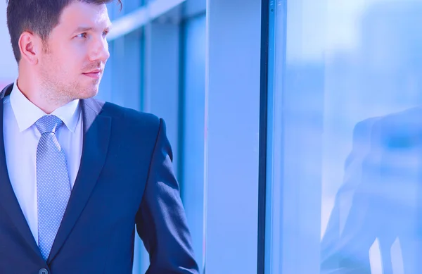 Retrato del hombre de negocios de pie cerca de la ventana en la oficina —  Fotos de Stock