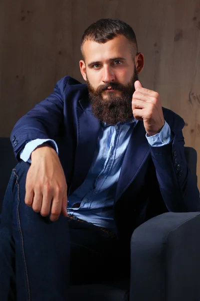 Businessman sitting the sofa in office lobby, isolated on dark background — Stock Photo, Image