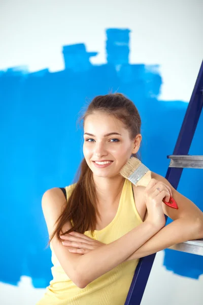 Happy beautiful young woman doing wall painting, standing near ladder — Stock Photo, Image