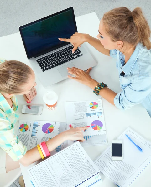 Två kvinnor arbetar tillsammans på kontoret, sitter på skrivbordet — Stockfoto