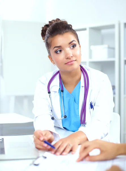 Læge og patient sidder på skrivebordet på kontoret - Stock-foto