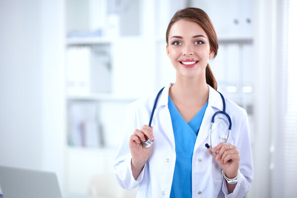 Portrait of young woman doctor with white coat standing in hospital