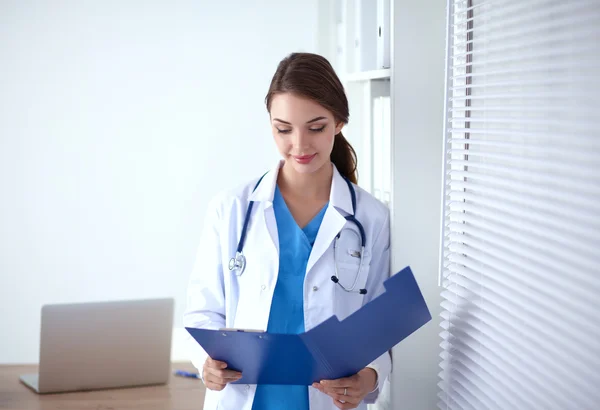Smiling female doctor with a folder in uniform standing at hospital — Stock Photo, Image