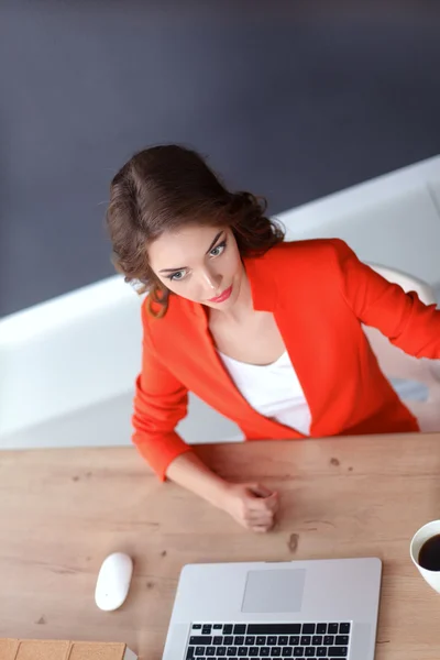 Mulher atraente sentada na mesa no escritório, trabalhando com computador portátil — Fotografia de Stock