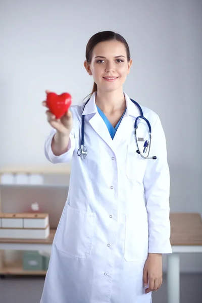 Genç bayan doktor elinde kırmızı bir kalp tutuyor. — Stok fotoğraf