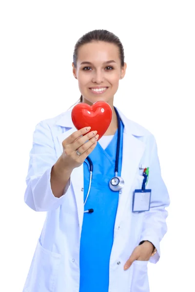 Positive female doctor standing with stethoscope and red heart symbol isolated — Stock Photo, Image