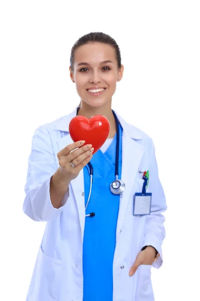 Positive female doctor standing with stethoscope and red heart symbol isolated — Stock Photo, Image