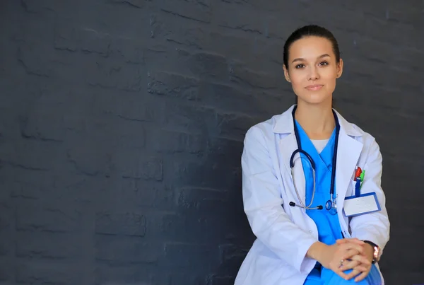 Молода жінка лікар сидить біля стіни — стокове фото