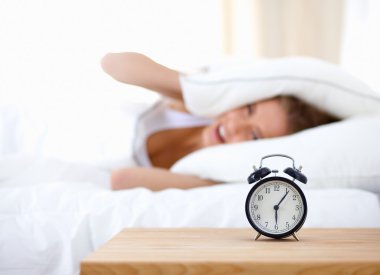 Evdeki yatak odasında uyuyan genç kadın ve çalar saat.