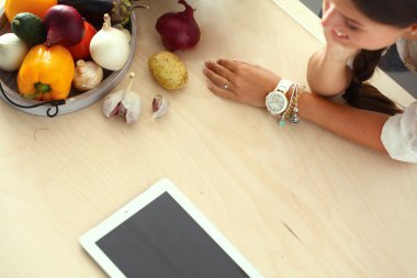 Mutfakta yemek yapmak için tablet bilgisayar kullanan genç bir kadın. .