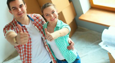 Genç Çift başparmak göstermek yukarıya onların yeni modern tasarım evinde mutlu