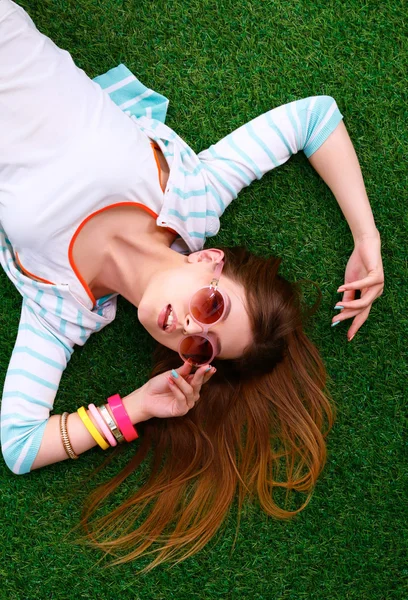 Mooie jonge vrouw liggend op het groene gras — Stockfoto