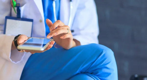 Jovem médico sentado com o seu telefone — Fotografia de Stock