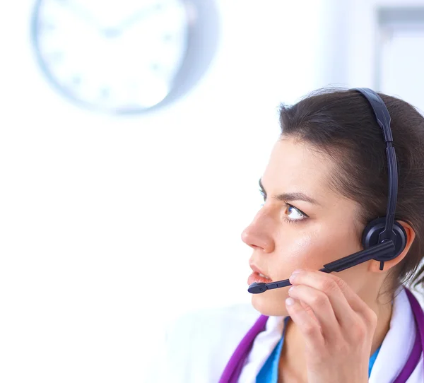 Médico con auriculares sentado detrás de un escritorio con portátil —  Fotos de Stock