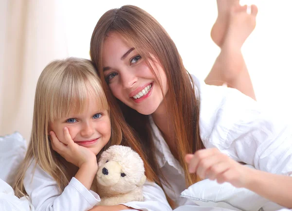 Vrouw en jonge meisje liggend in bed glimlachen — Stockfoto