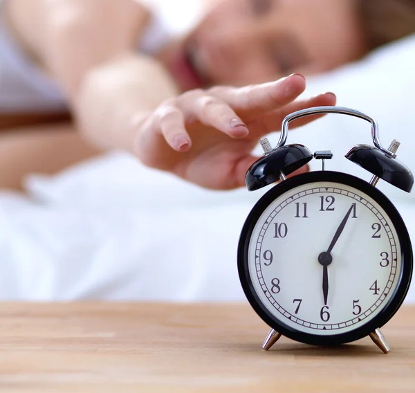 Young sleeping woman and alarm clock in bedroom at home Royalty Free Stock Images