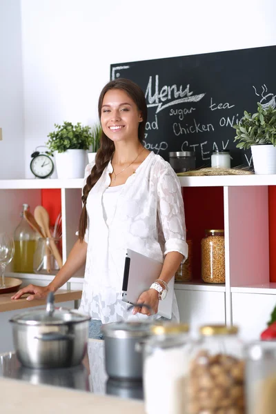Young woman using a tablet computer to cook in her kitchen . — Stock Photo, Image