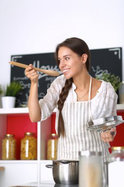 Mutfakta ahşap kaşıkla yemek pişiren kadın