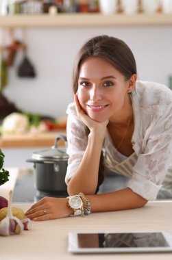 Mutfakta masanın yanında duran genç bir kadın.