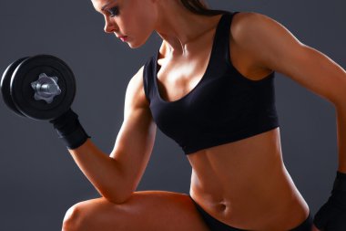 Atletik kadın dambıllarla kaslarını şişiriyor.