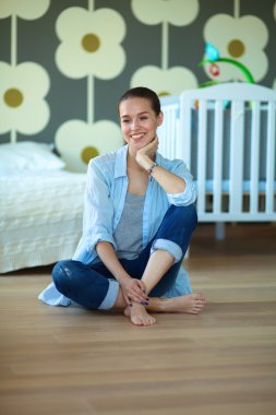 Çocuk karyolası yakın katta oturan genç kadın.