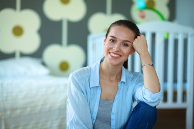 Çocuk karyolası yakın katta oturan genç kadın.