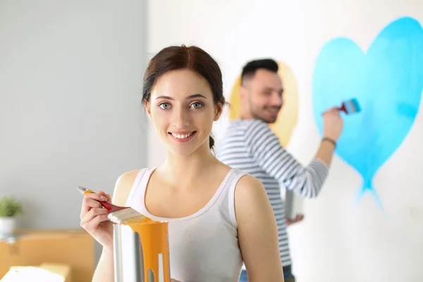 Portret van gelukkig interieur wand via lachende jong koppel-schilderij van nieuwe huis — Stockfoto