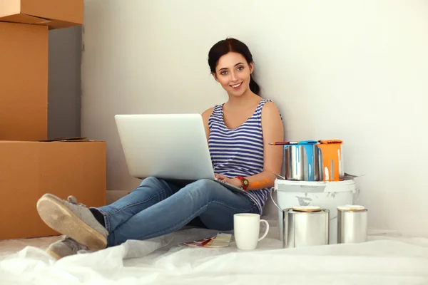 Fiatal nő portré, míg a festészet új lakás, ül a laptop — Stock Fotó