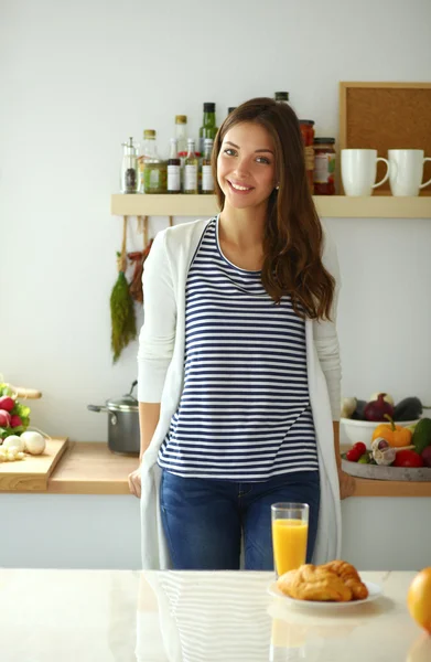 Ung kvinna med glas juice och kakor stående i köket . — Stockfoto