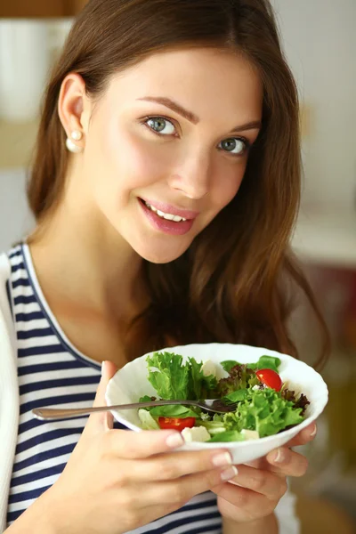 Giovane donna mangiare insalata e tenere un'insalata mista — Foto Stock