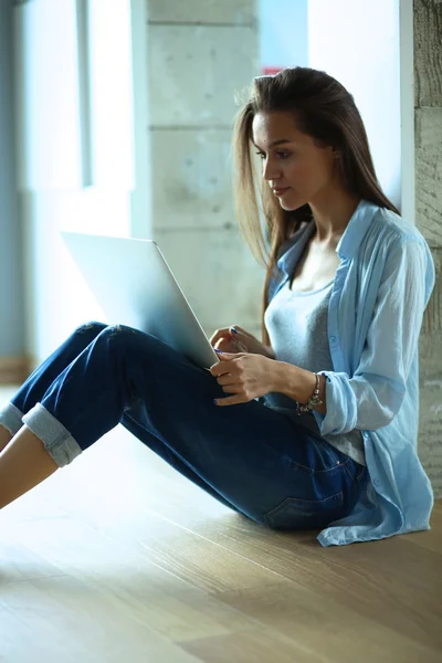 Unga vackra kvinnan hemma sitter på golvet med laptop — Stockfoto