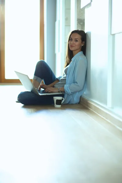 Unga vackra kvinnan hemma sitter på golvet med laptop — Stockfoto