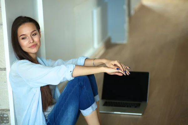 Unga vackra kvinnan hemma sitter på golvet med laptop — Stockfoto