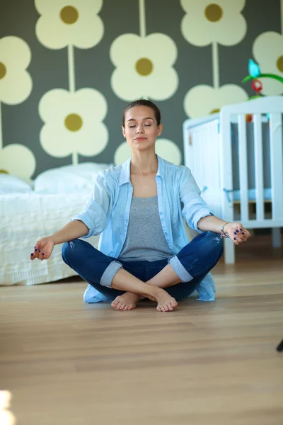 Young woman doing yoga at home in the lotus position — Stock Photo, Image