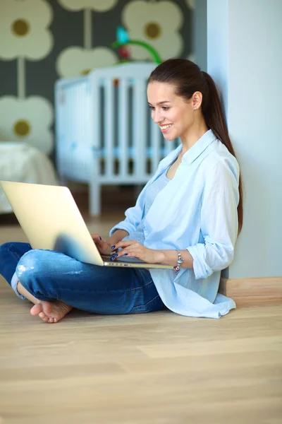 Unga vackra kvinnan hemma sitter på golvet med laptop — Stockfoto