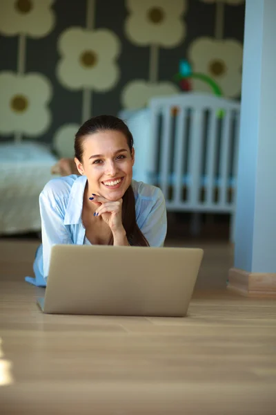 Unga vackra kvinnan hemma sitter på golvet med laptop — Stockfoto