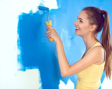 Güzel genç bir kadın duvar boyuyor.