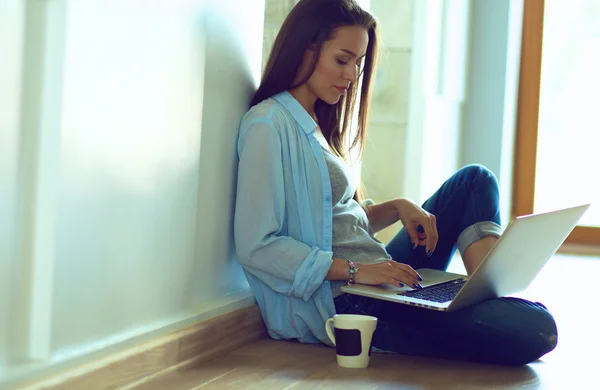 Unga vackra kvinnan hemma sitter på golvet med laptop — Stockfoto