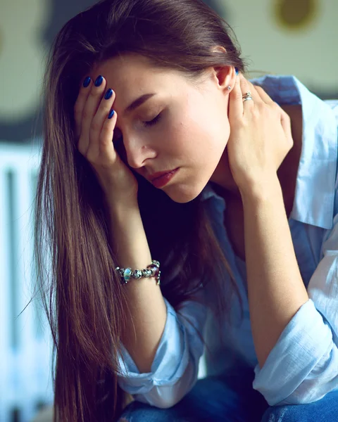 Yatakta çocuk karyolası yakın oturan genç yorgun kadın.