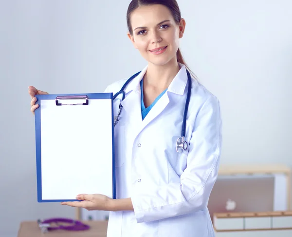 Médico sonriente con una carpeta en uniforme de pie en el hospital — Foto de Stock