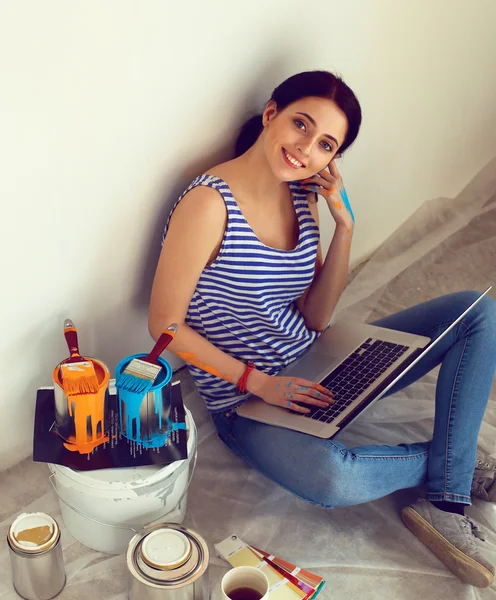 Young woman portrait while painting new apartment ,sitting with laptop — Stock Photo, Image