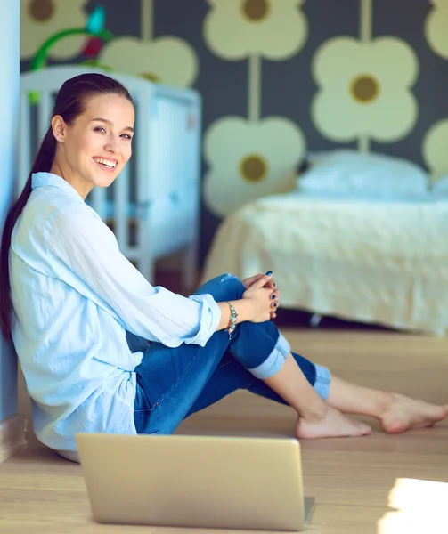 Jonge mooie vrouw thuis zittend op de vloer met laptop — Stockfoto