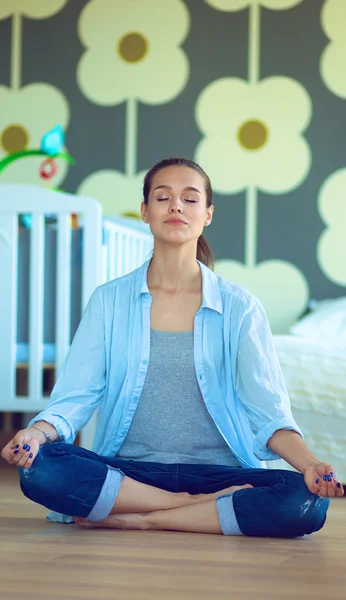 Mujer joven haciendo yoga en casa en la posición de loto — Foto de Stock