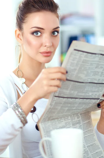 Nette Geschäftsfrau mit Zeitung sitzt an ihrem Schreibtisch im hellen Büro — Stockfoto