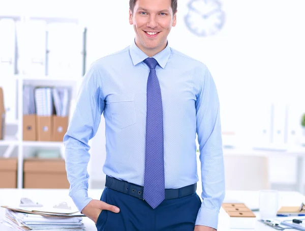 Hombre de negocios o gerente de pie contra su escritorio en la oficina — Foto de Stock