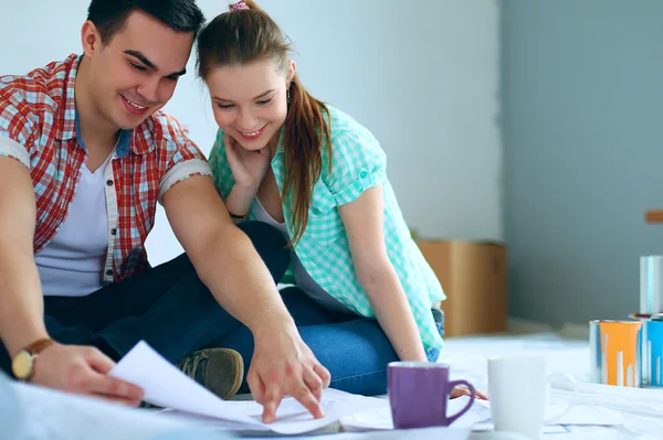 Junges Paar sitzt auf dem Boden und rechnet über seine Ersparnisse — Stockfoto