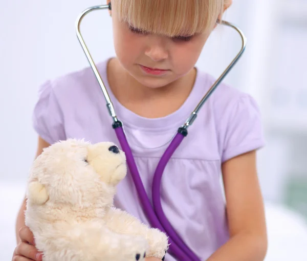 Kleines Mädchen untersucht Teddybär mit Stethoskop — Stockfoto