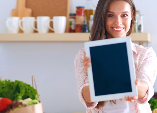 Mutfakta yemek yapmak için tablet bilgisayar kullanan genç bir kadın. . — Stok fotoğraf
